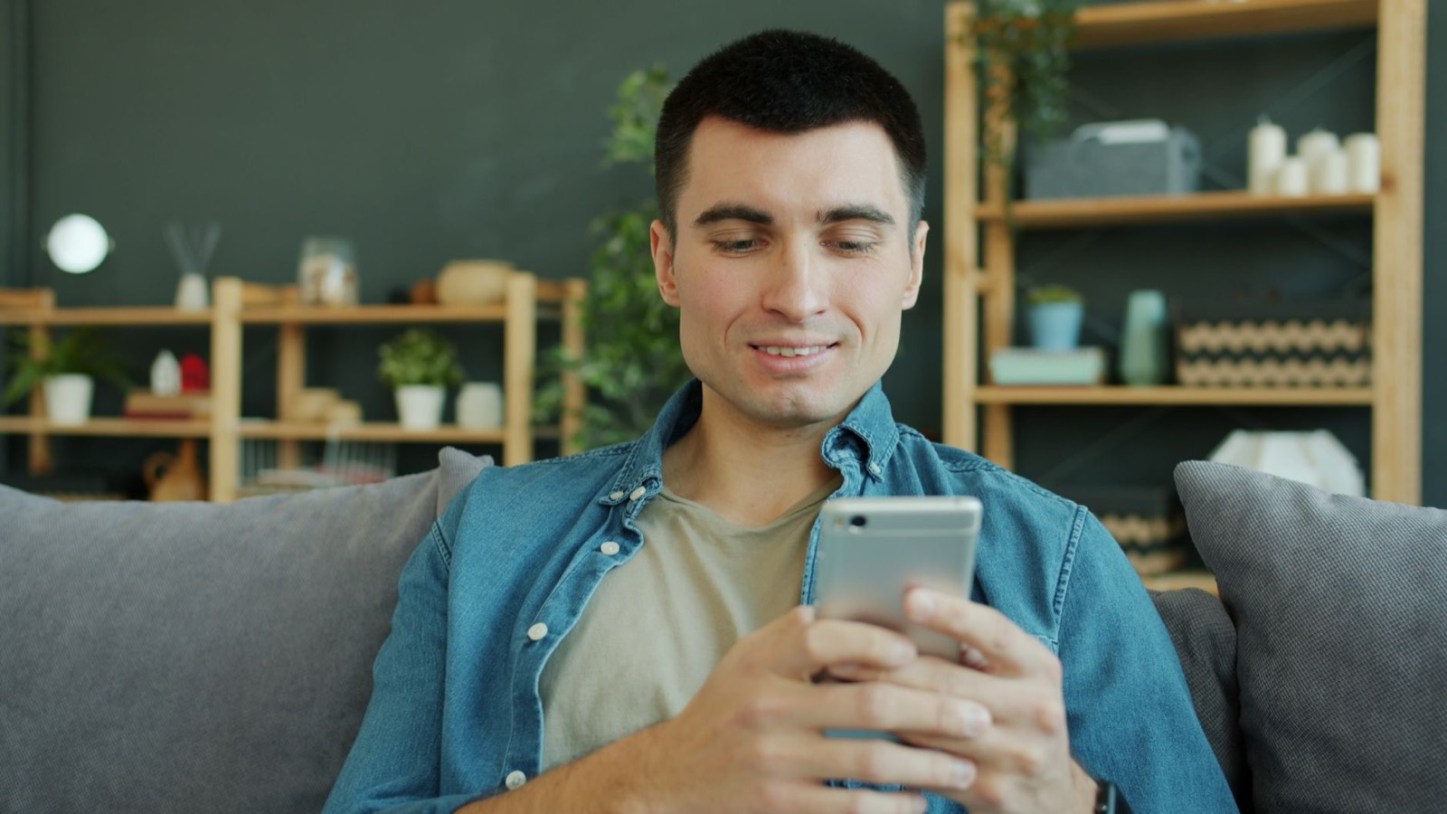 Propriétaire consultant son smartphone dans son salon pour poser une question immobilière